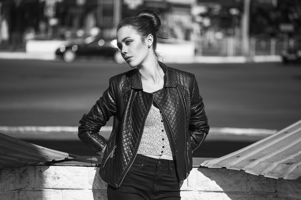 Concepto de belleza femenina. Retrato de una joven de moda en jeans negros casuales, chaqueta negra, top blanco, gafas de sol y bolsita posando en la calle. Cabello y piel perfectos. Estilo Vogue. tiro al aire libre
 - Foto, imagen