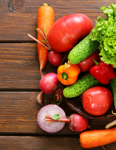 erilaisia vihanneksia salaattia varten (kurkut, tomaatit, salaatti, retiisit, porkkanat) puupohjalla
 - Valokuva, kuva