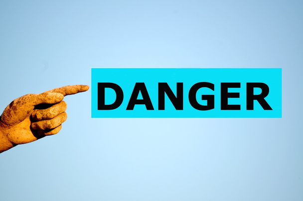 палец с прямоугольной светло-голубой этикеткой Опасность
 - Фото, изображение