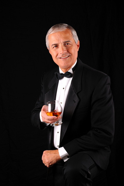 Middle aged man wearing a tuxedo with brandy snifter - Fotoğraf, Görsel