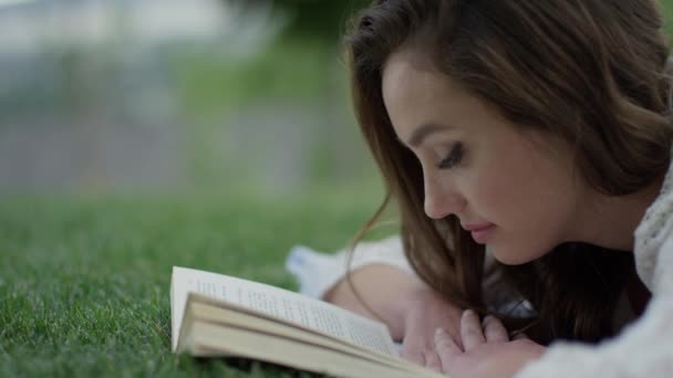 woman reading book in grass - 映像、動画