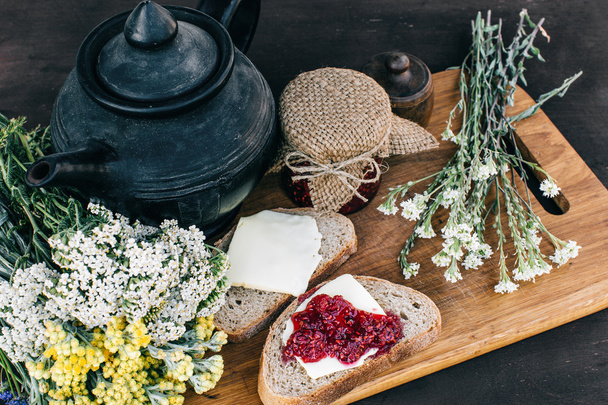 Raspberry jam and bread with butter in a jar and hot herbal tea on the wooden table Lunch breakfast - Fotoğraf, Görsel