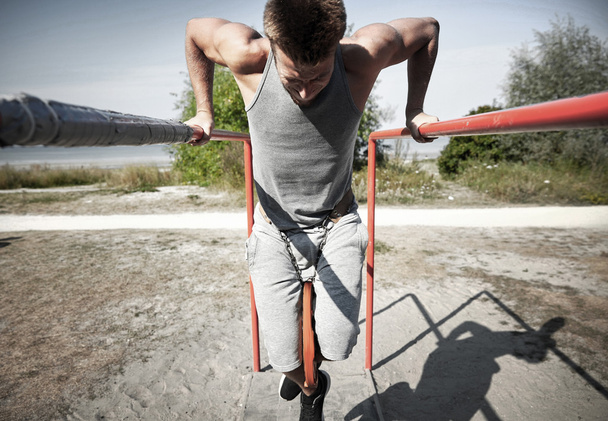 young man exercising on parallel bars outdoors - Foto, afbeelding