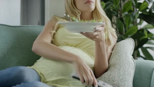 pregnant woman eating salad on sofa - Záběry, video