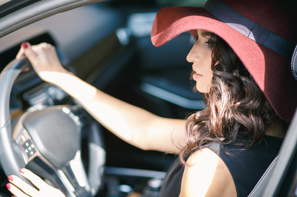 Close-up portrait of gorgeous young brunette woman driving an expensive car - Foto, afbeelding
