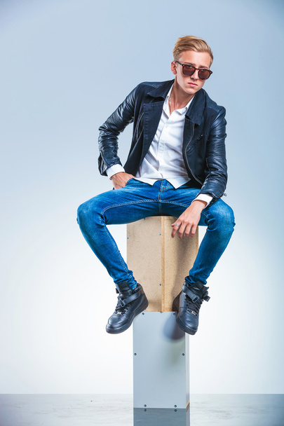boy holding his hand in pocket is posing while sitting on boxes - Zdjęcie, obraz