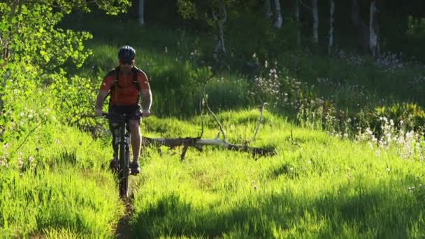 Man riding mountain bike through grassy hill - Video, Çekim