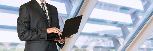 Podnikatel v černém obleku drží notebook - Fotografie, Obrázek