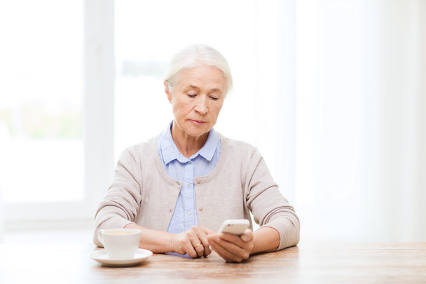 ηλικιωμένη γυναίκα με μηνύματα smartphone στο σπίτι - Φωτογραφία, εικόνα