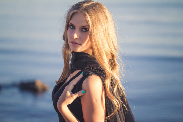 Pretty young blonde woman in a summer evening over sea bay background - Φωτογραφία, εικόνα
