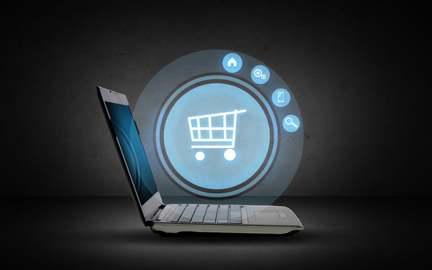 laptop computer with shopping cart icon projection - Foto, Imagen