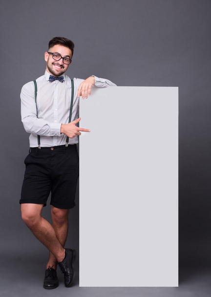 Hipster man posing with blank poster - Фото, изображение