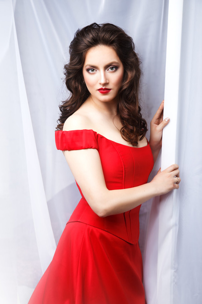 Close-up portrait of beautiful brunette young woman in elegant luxury red dress - 写真・画像