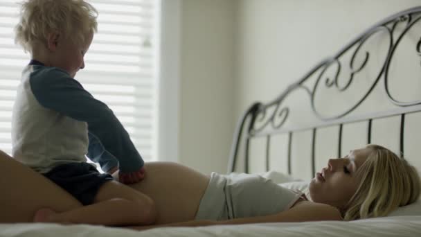 pregnant mother and son laying on bed - Filmagem, Vídeo