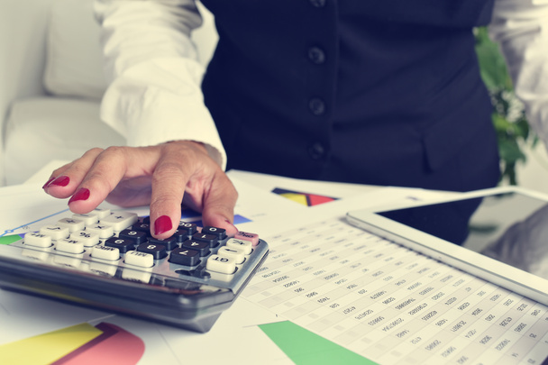 mujer de negocios usando una calculadora electrónica en su oficina
 - Foto, Imagen