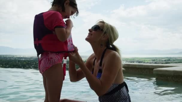 Madre ayudando a hija a ponerse chaleco salvavidas
 - Imágenes, Vídeo