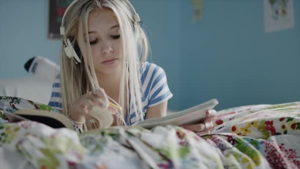 girl doing homework and listening to music - Záběry, video