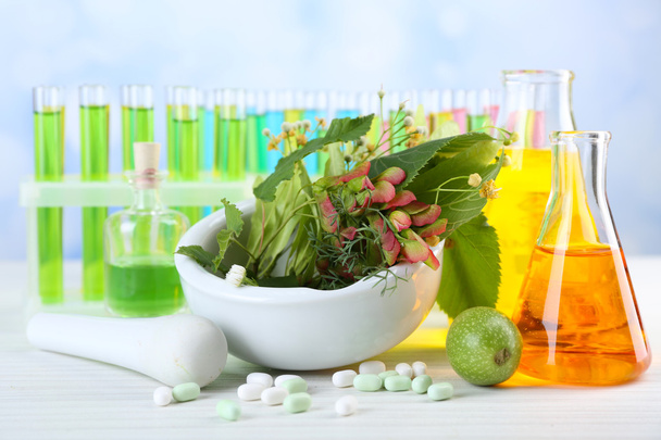 Herbs in mortar, test tubes and pills,  on table, on light background - Φωτογραφία, εικόνα