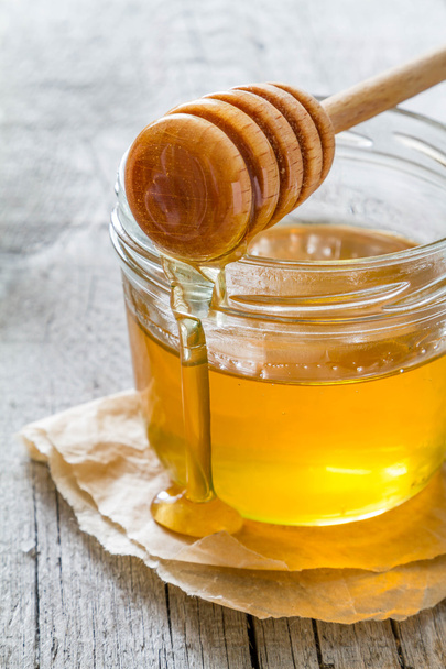 Honey in glass jar and dipper - Фото, изображение