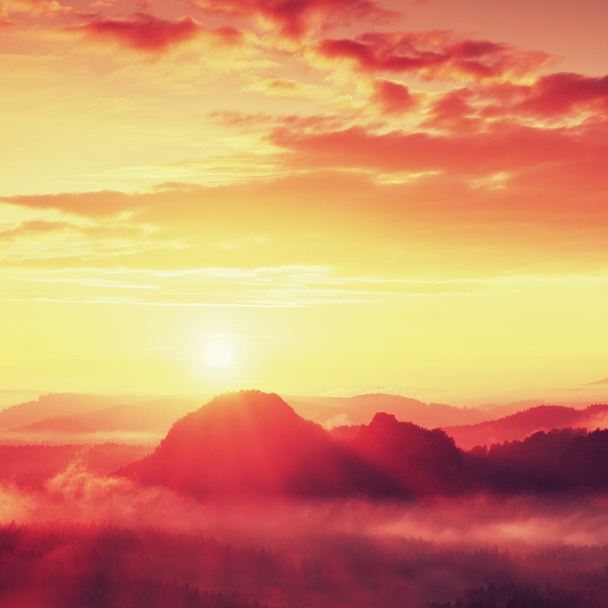Paysage rêveur brumeux avec brouillard automnal entre collines et ciel orange au lever du soleil tôt
 - Photo, image