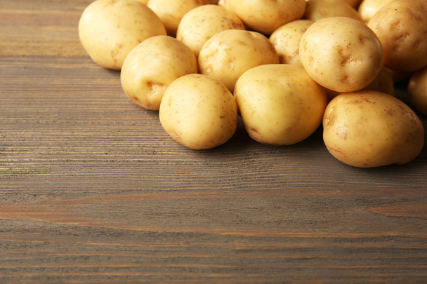 New potatoes on wooden background - Foto, afbeelding