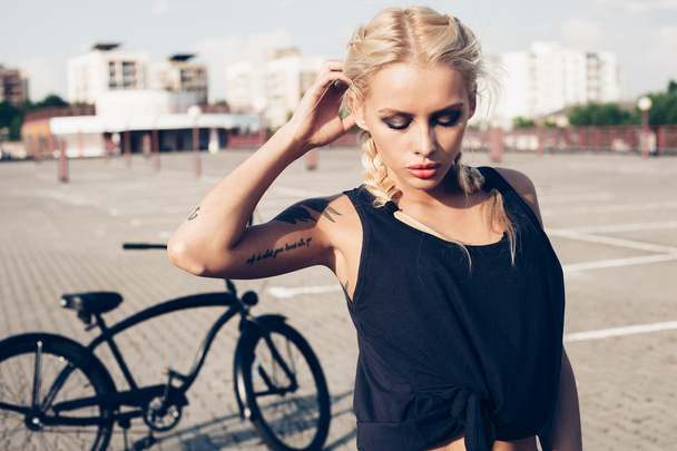 Pretty blonde woman with bike in city - Foto, afbeelding