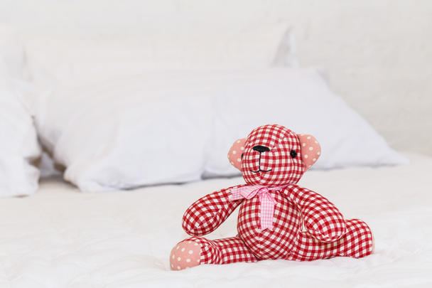 Red bear doll on bed - Фото, изображение