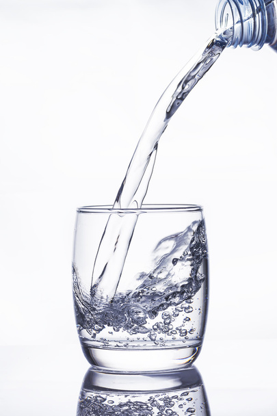 Water pouring into the glass on white - Foto, Bild