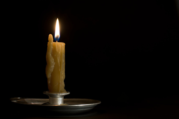 Antique metal candlestick with burning candle on black backgroun - Fotografie, Obrázek