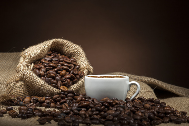 weiße Tasse mit Kaffeebohnen auf dunklem Hintergrund - Foto, Bild