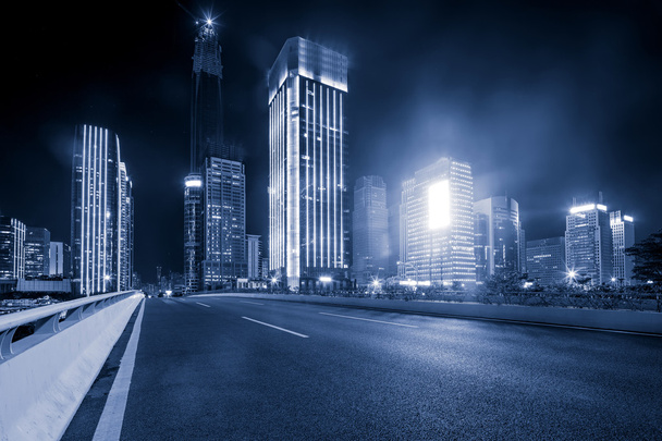 aszfalt út közelében felhőkarcolók éjjel - Fotó, kép