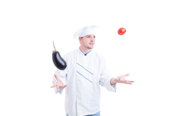 Chef ou cuisinier jonglant avec des légumes une aubergine et tomate
 - Photo, image