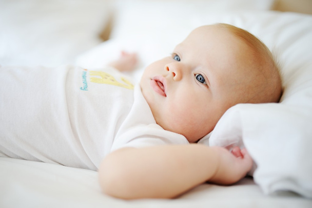 portrait of baby with blue eyes. A child resting on a bed - Photo, Image