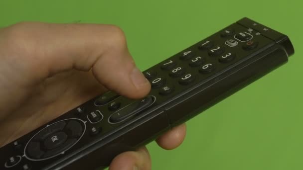 Αρσενική χέρι αλλάζει κανάλια με απομακρυσμένο έλεγχο σε μια πράσινη οθόνη. Πλευρά πυροβόλησε - Πλάνα, βίντεο