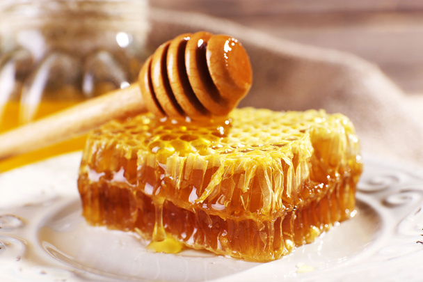 Honeycomb, dipper on white plate and pot of honey closeup - Fotó, kép