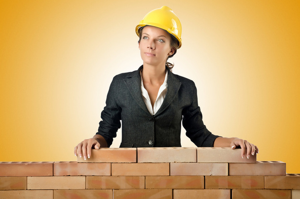 Nuori nainen rakentaja lähellä tiili seinään
 - Valokuva, kuva