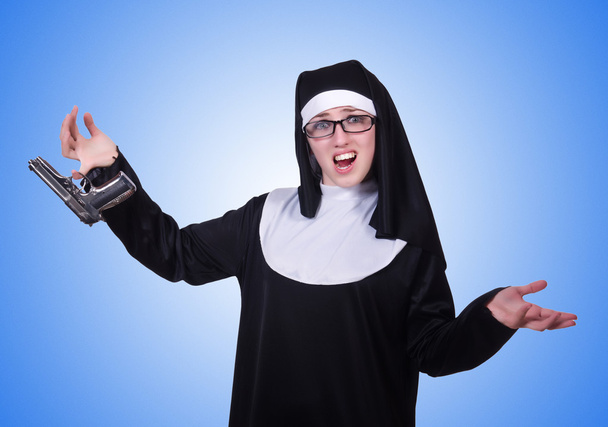 Монахиня с пистолетом изолированы на синий
 - Фото, изображение