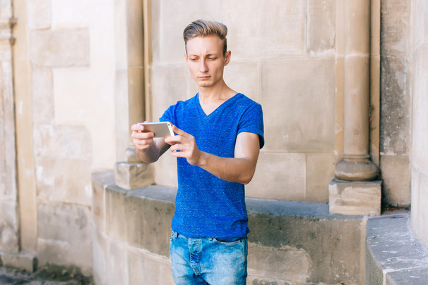 Молодий чоловік з мобільним телефоном на вулиці
 - Фото, зображення