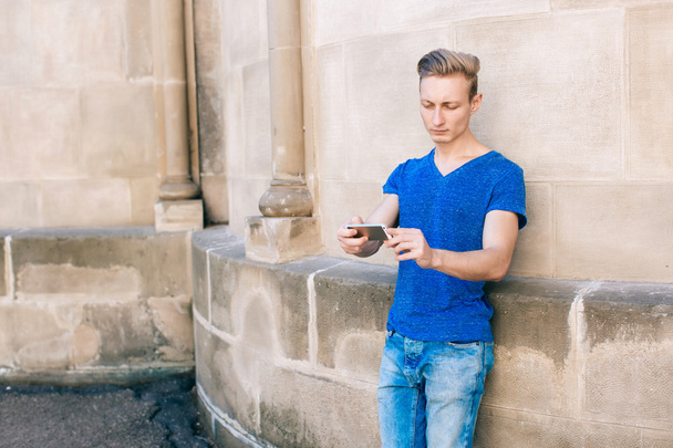 Молодий чоловік з мобільним телефоном на вулиці
 - Фото, зображення
