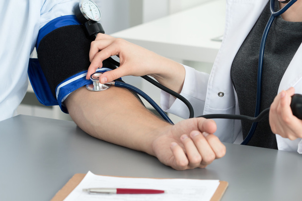 Naispuolinen lääkäri, joka mittaa potilaan verenpainetta
 - Valokuva, kuva