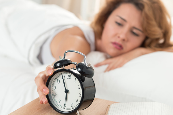 Young sleepy woman trying to turn off the alarm clock - Фото, зображення