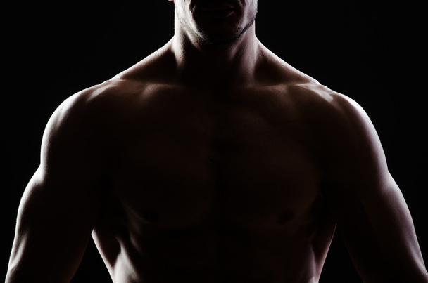 Musclé homme posant dans sombre studio - Photo, image