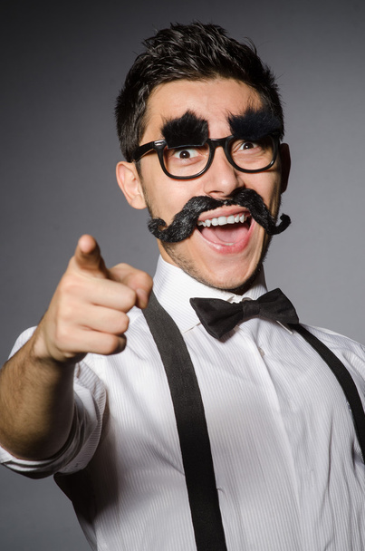 Young caucasian man with false moustache against gray - Foto, Bild