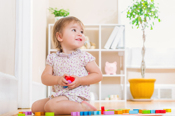 Tout-petit fille souriant et jouant avec des blocs jouets
 - Photo, image