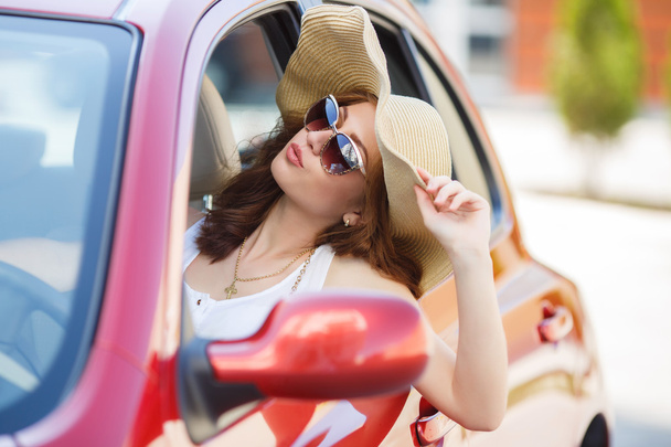 Happy woman driving a red compact car - Zdjęcie, obraz