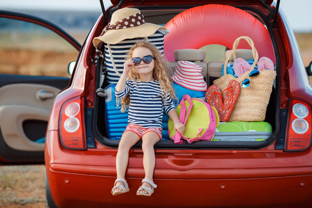 Portrait of a little girl sitting in the trunk of a car - Foto, afbeelding