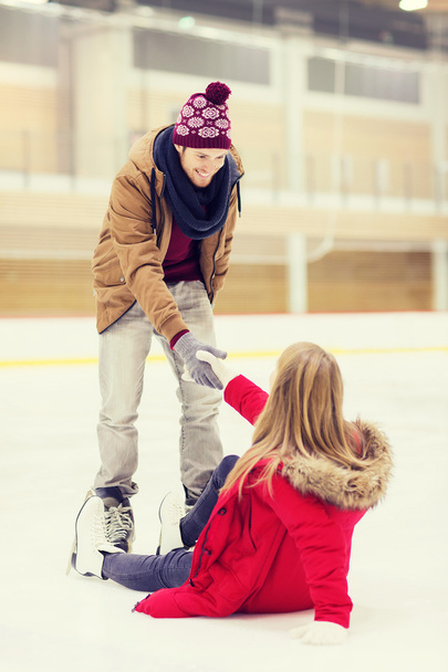man helping women to rise up on skating rink - Φωτογραφία, εικόνα