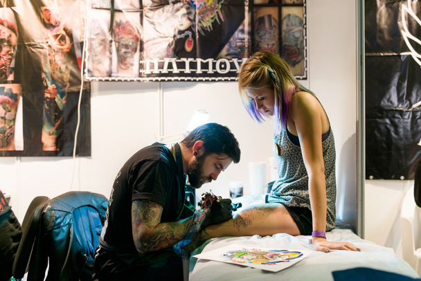 MINSK, BELARUS - SEPTEMBER 19, 2015: Professional tattoo artist doing tattoo on woman leg. - Φωτογραφία, εικόνα