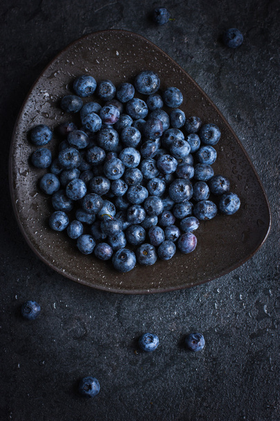Fresh blueberry on black plate with water drops - Foto, afbeelding