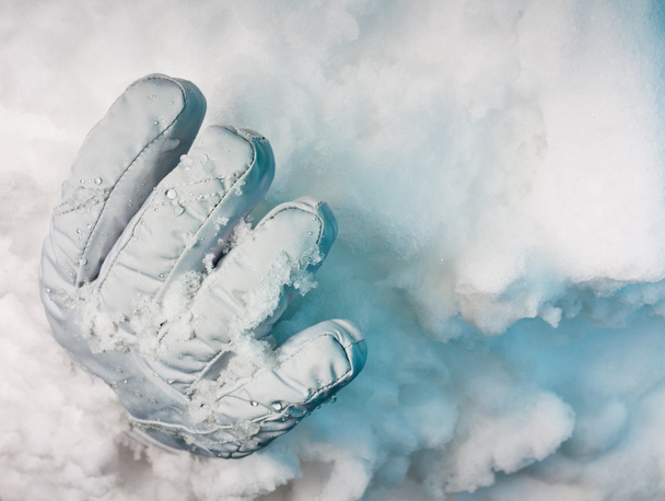 Enterrado vivo. Un guante sobresaliendo de una deriva de nieve con profundas sombras azules
. - Foto, Imagen